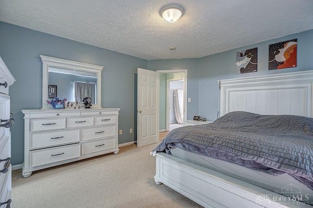 bedroom featuring baseboards, light carpet, and a textured ceiling