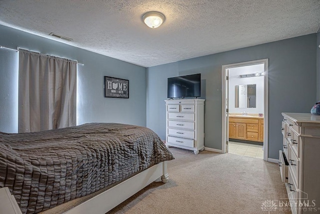 bedroom with visible vents, a textured ceiling, ensuite bath, baseboards, and light colored carpet