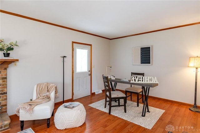 dining area featuring baseboards, wood finished floors, a fireplace, and crown molding