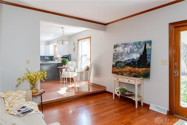 living room featuring a notable chandelier, visible vents, baseboards, and wood finished floors