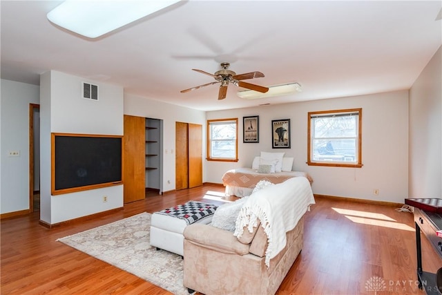 living area featuring visible vents, ceiling fan, baseboards, and wood finished floors