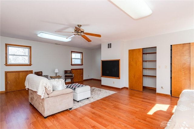 living area with baseboards, a ceiling fan, visible vents, and light wood-type flooring