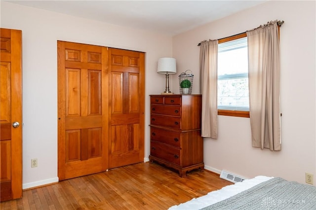 bedroom with visible vents, baseboards, a closet, and wood finished floors