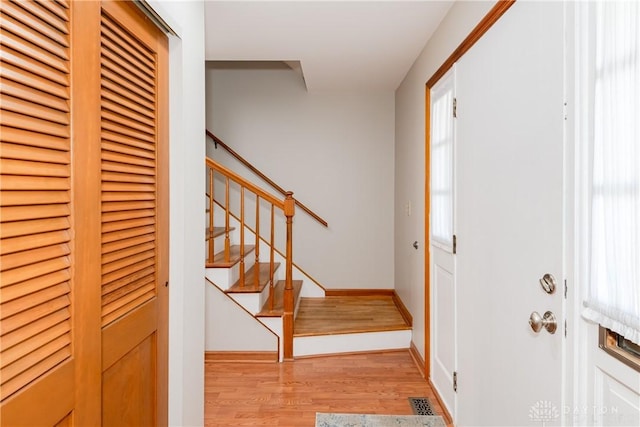 entrance foyer featuring baseboards, light wood-style flooring, and stairs