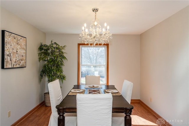 dining area with baseboards, an inviting chandelier, and wood finished floors