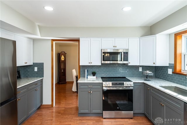 kitchen featuring light wood-style flooring, appliances with stainless steel finishes, white cabinetry, and gray cabinetry