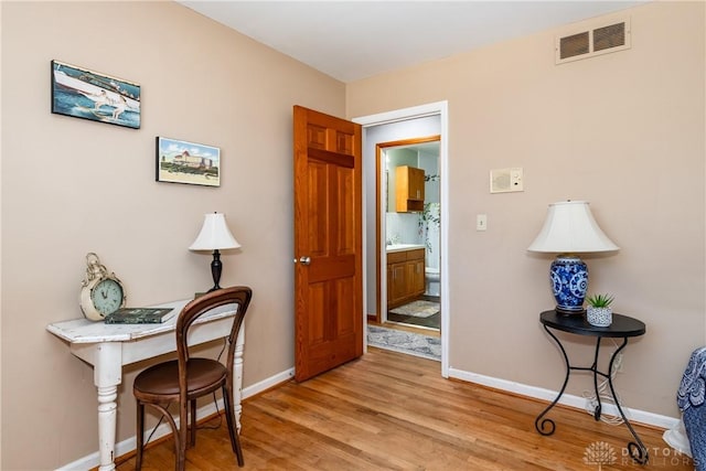 office area featuring light wood-style flooring, baseboards, and visible vents