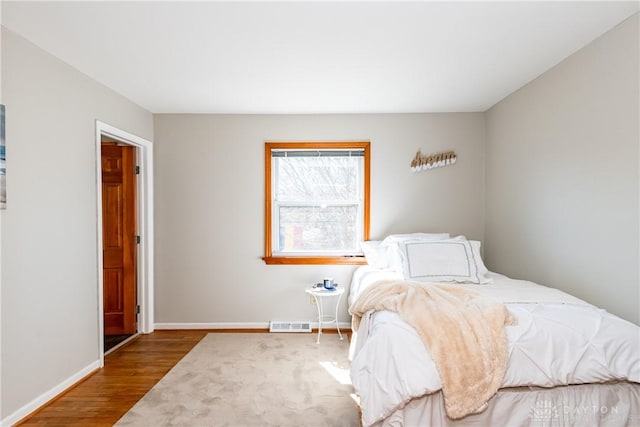 bedroom with visible vents, wood finished floors, and baseboards