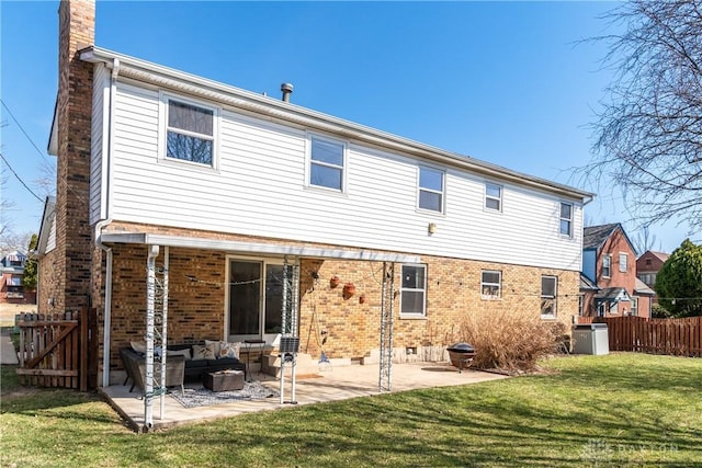 rear view of house featuring an outdoor living space, a yard, a chimney, a patio area, and brick siding