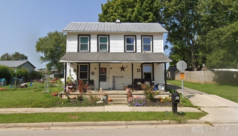 view of front of property with metal roof, a porch, a front lawn, and fence