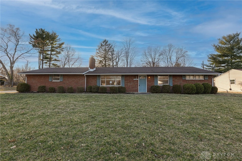 single story home featuring brick siding, a chimney, and a front lawn