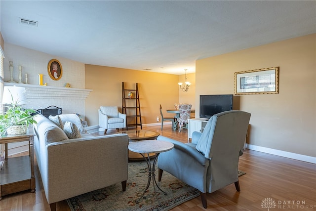 living room featuring a chandelier, a fireplace, baseboards, and wood finished floors