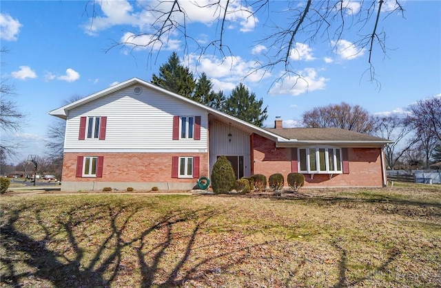 split level home featuring a front lawn, brick siding, and a chimney