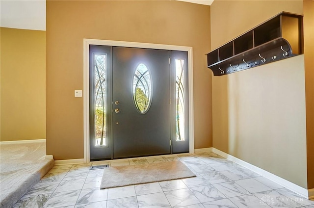 foyer with baseboards and marble finish floor