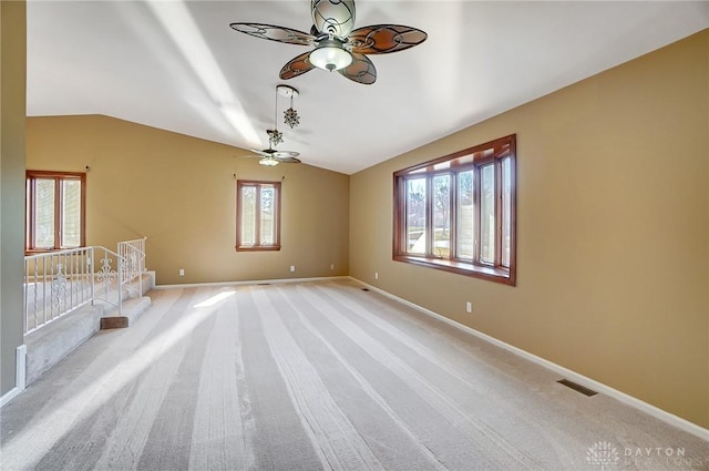 spare room featuring light carpet, visible vents, baseboards, and lofted ceiling