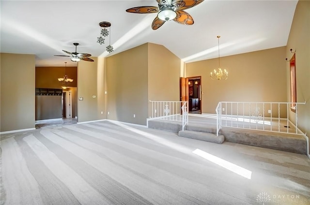 unfurnished living room featuring ceiling fan with notable chandelier, baseboards, lofted ceiling, and carpet floors