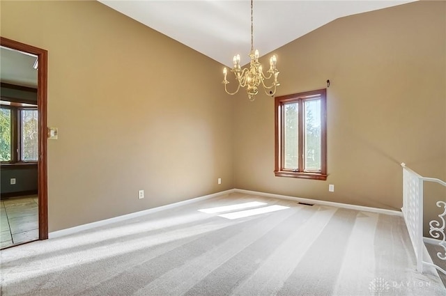 carpeted empty room with baseboards, a chandelier, and vaulted ceiling