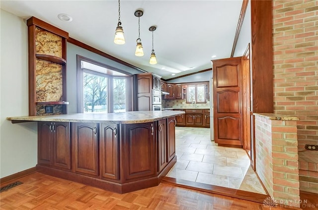 kitchen featuring baseboards, a peninsula, light countertops, pendant lighting, and crown molding