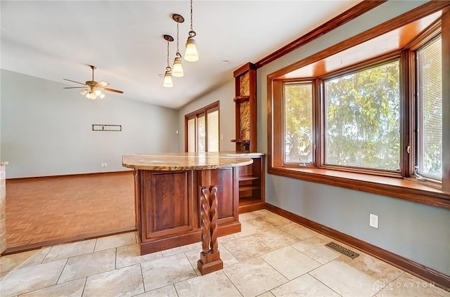 kitchen featuring lofted ceiling, decorative light fixtures, baseboards, and visible vents