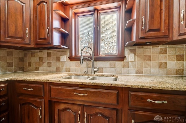 kitchen with light stone countertops, tasteful backsplash, and a sink