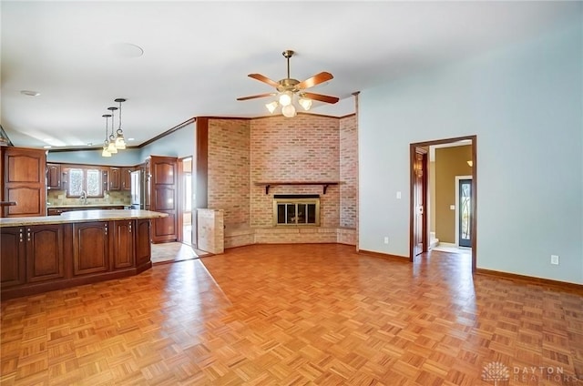 kitchen with baseboards, open floor plan, light countertops, a fireplace, and a sink