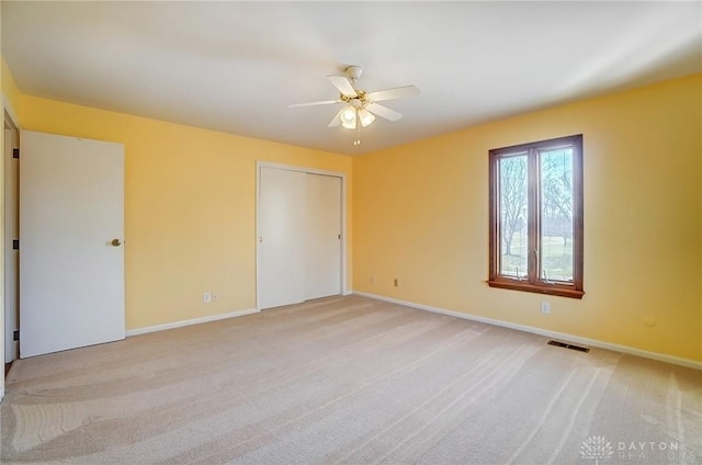 unfurnished bedroom featuring light carpet, visible vents, ceiling fan, and baseboards