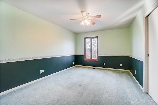 empty room featuring baseboards, visible vents, carpet floors, and ceiling fan