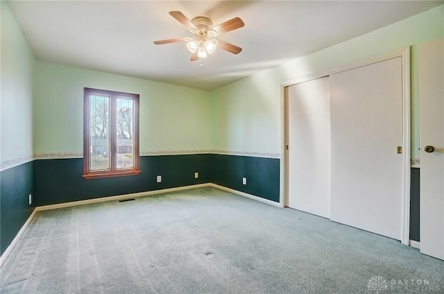 unfurnished bedroom featuring a closet, a ceiling fan, visible vents, and carpet floors