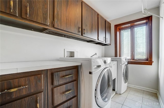 washroom with baseboards, cabinet space, separate washer and dryer, and light tile patterned flooring