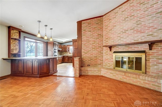 kitchen with pendant lighting, a peninsula, light countertops, baseboards, and a brick fireplace