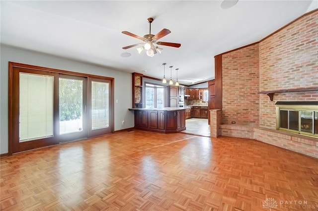 unfurnished living room with a brick fireplace and ceiling fan