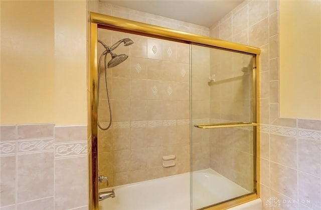 bathroom with tile walls and shower / bath combination with glass door