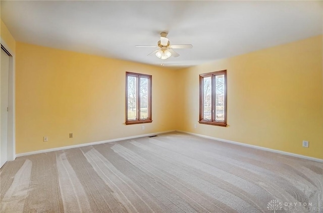 empty room featuring ceiling fan, baseboards, and light carpet