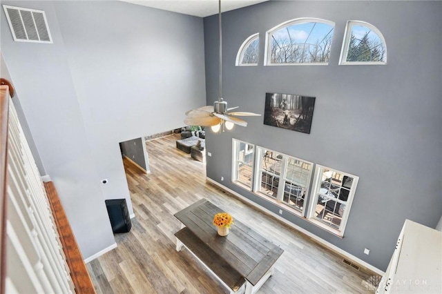 interior space with a ceiling fan, wood finished floors, visible vents, and baseboards