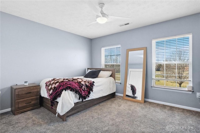 bedroom featuring a ceiling fan, visible vents, baseboards, and carpet floors