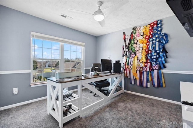 carpeted office space with visible vents, a textured ceiling, baseboards, and ceiling fan