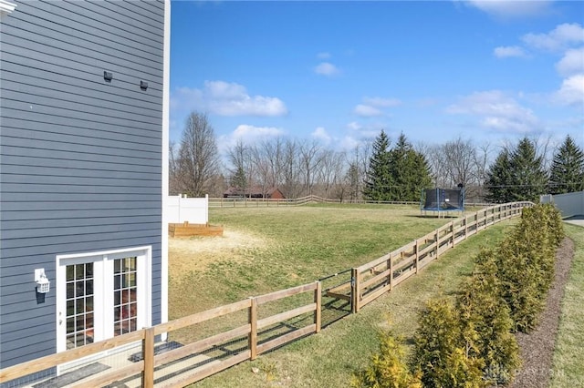 view of yard featuring a rural view, a trampoline, and fence