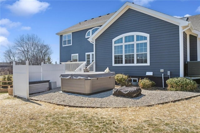 back of house featuring fence and a hot tub