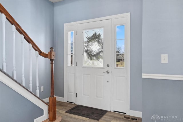 foyer with visible vents, stairway, baseboards, and wood finished floors