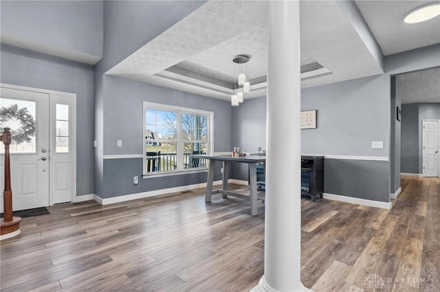 foyer with a raised ceiling, baseboards, and wood finished floors