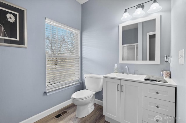 full bath with vanity, wood finished floors, baseboards, visible vents, and toilet