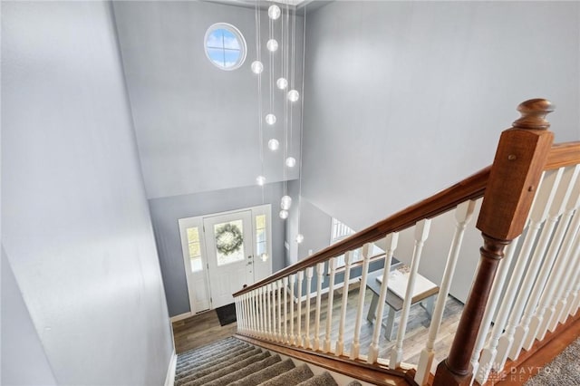 entrance foyer with baseboards, wood finished floors, and a towering ceiling