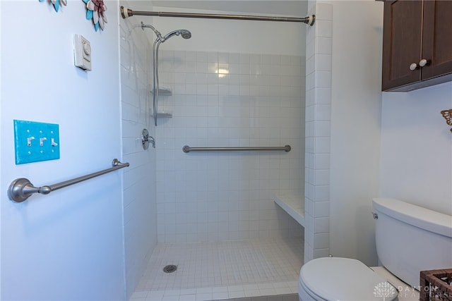 bathroom with a tile shower and toilet