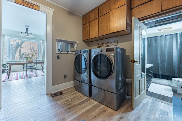 laundry room with visible vents, ornamental molding, cabinet space, separate washer and dryer, and light wood finished floors