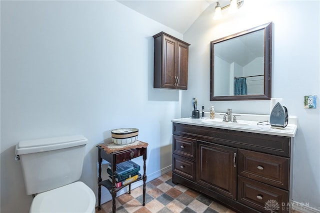 full bath with toilet, vanity, baseboards, and vaulted ceiling