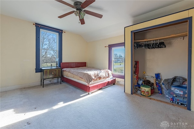 carpeted bedroom featuring lofted ceiling, multiple windows, a closet, and ceiling fan