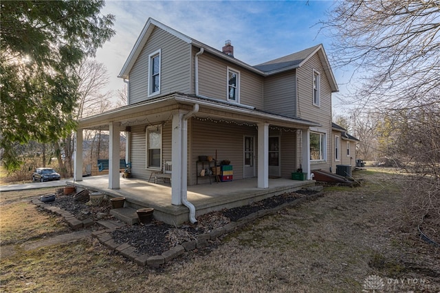 back of house featuring a porch and a chimney