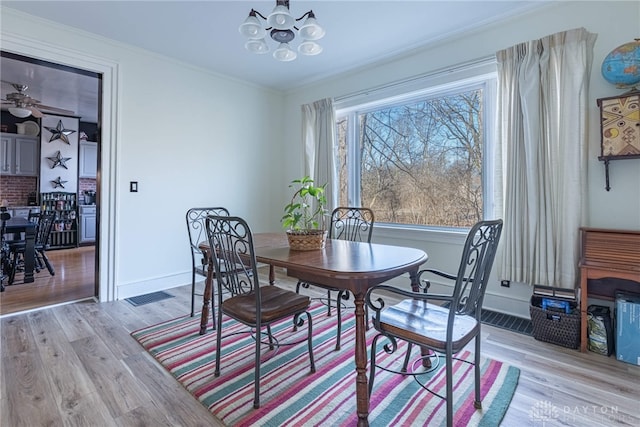 dining area with an inviting chandelier, crown molding, light wood-style flooring, and baseboards