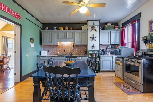 kitchen with stainless steel appliances, a ceiling fan, light wood-style floors, and a sink