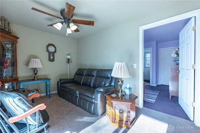 living room with ceiling fan, baseboards, and carpet